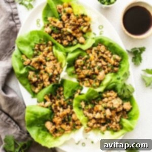 Finished PF Chang's style lettuce wraps arranged on a platter with fresh lettuce cups and green onion garnish.