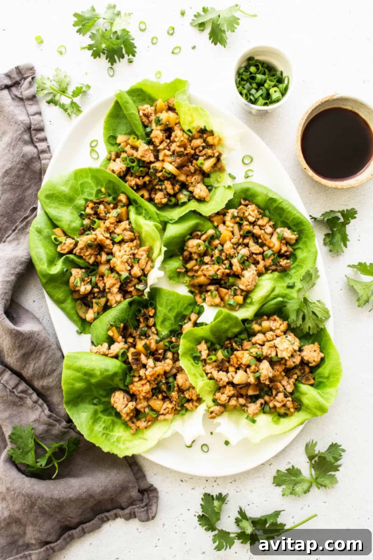 A serving platter filled with fresh butter lettuce leaves and a generous bowl of savory chicken filling, ready for guests to assemble their own wraps.