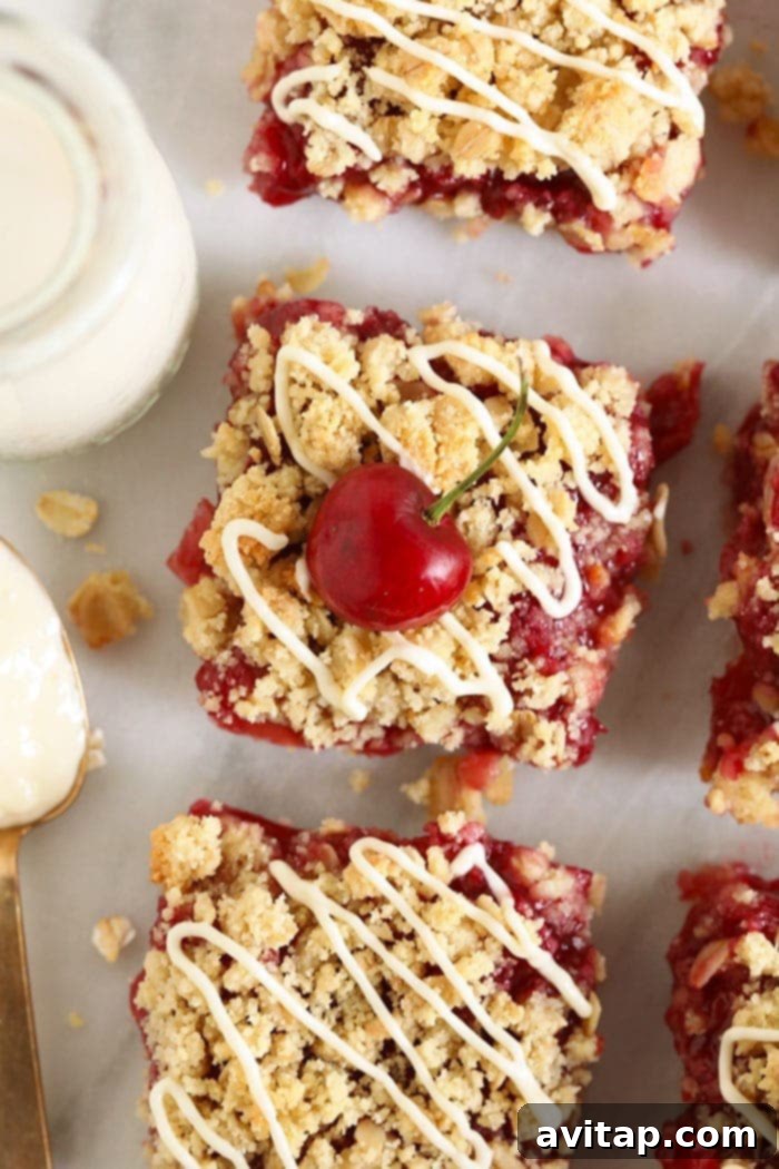 Make these cherry cobbler bars the next time you need a little sweet treat! These cherry cobbler bars are made with fresh cherries and a delicious almond flour crust. Have no fear, cherry season is here! Close-up of freshly baked and glazed cherry cobbler bars on a white plate, served with a glass of milk, showcasing the rich cherry filling and crumbly topping.