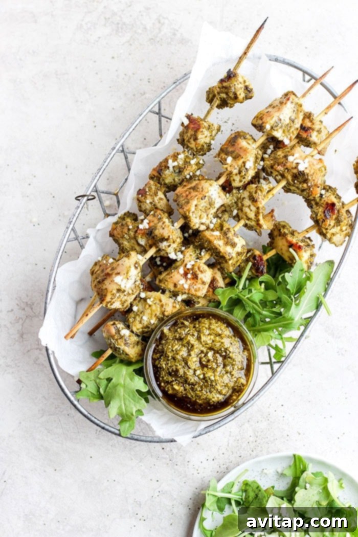Delicious Pesto Chicken Skewers, Ready to Enjoy Cooked pesto chicken skewers with a golden-brown char, nestled in a serving basket, garnished with fresh herbs.
