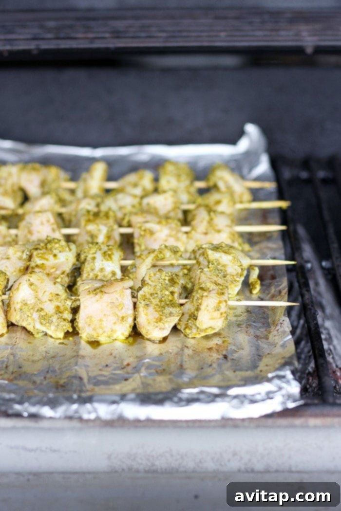 Sizzling Pesto Chicken Skewers on the Grill Pesto chicken skewers sizzling on a hot grill, showing perfect char marks and juicy texture.