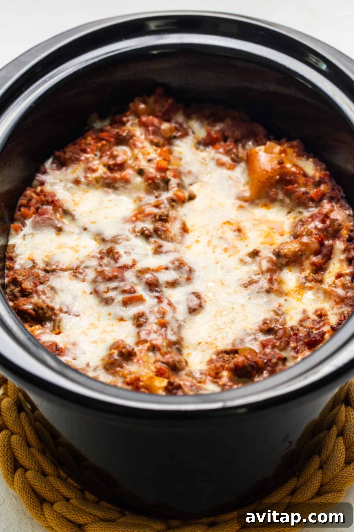 A rustic, hearty pot of freshly cooked lasagna sits on a wooden table, steam gently rising, ready to be served.