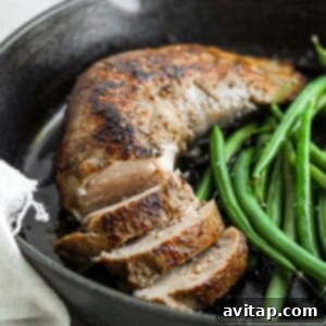Pork tenderloin searing in a cast iron skillet.
