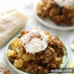 A close-up of a serving of warm apple crisp, perfectly baked with a golden topping, ready to be enjoyed with a scoop of ice cream.