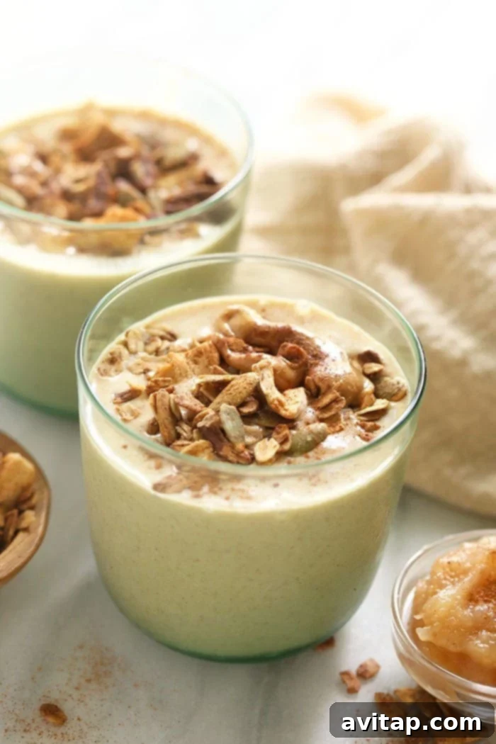 apple smoothie in a glass topped with granola