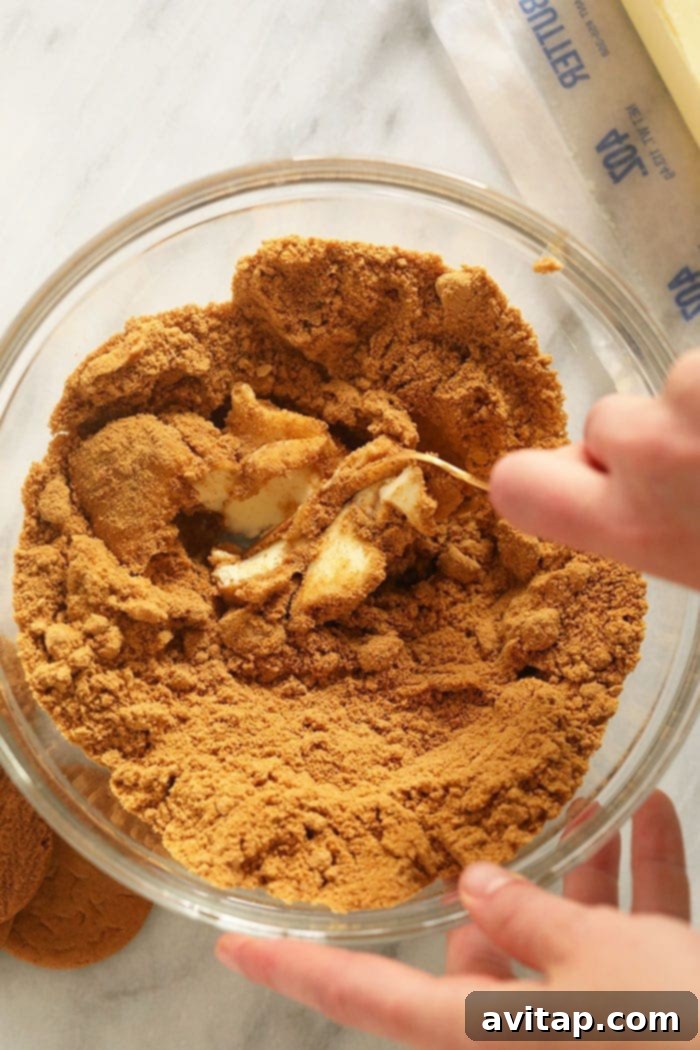 Mixing Gingersnap Cookie Crust Gingersnap cookie crust ingredients being mixed in a bowl with a spatula, creating the perfect base for pumpkin cheesecake bars.