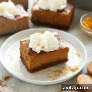 Pumpkin Cheesecake Bar Serving A single pumpkin cheesecake bar on a plate, garnished with whipped cream and gingersnap crumbs.