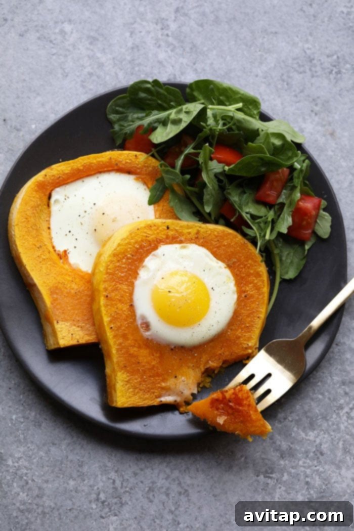 Two butternut squash eggs in a frame on a white plate with a fork