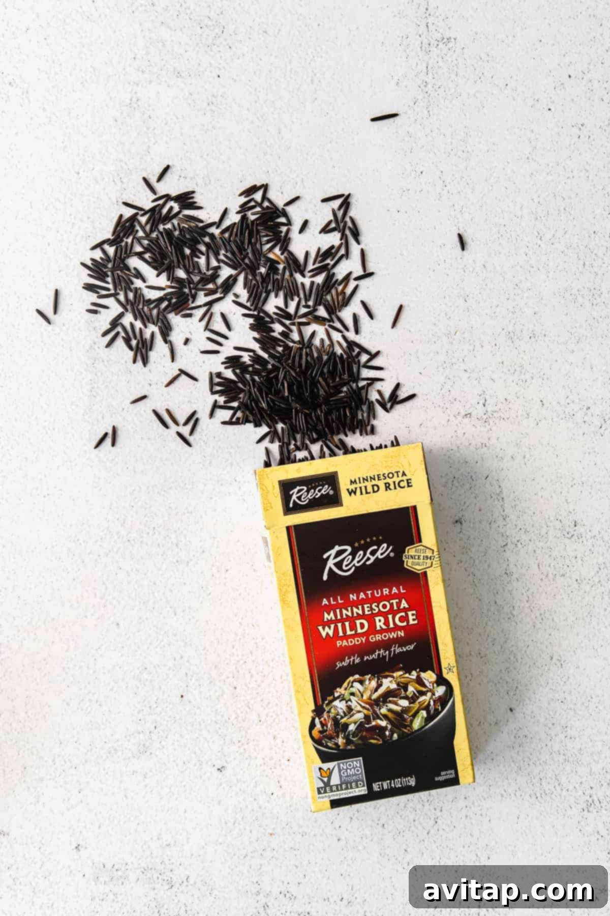 Dry wild rice grains spilling out of a brown package, illustrating its raw form.