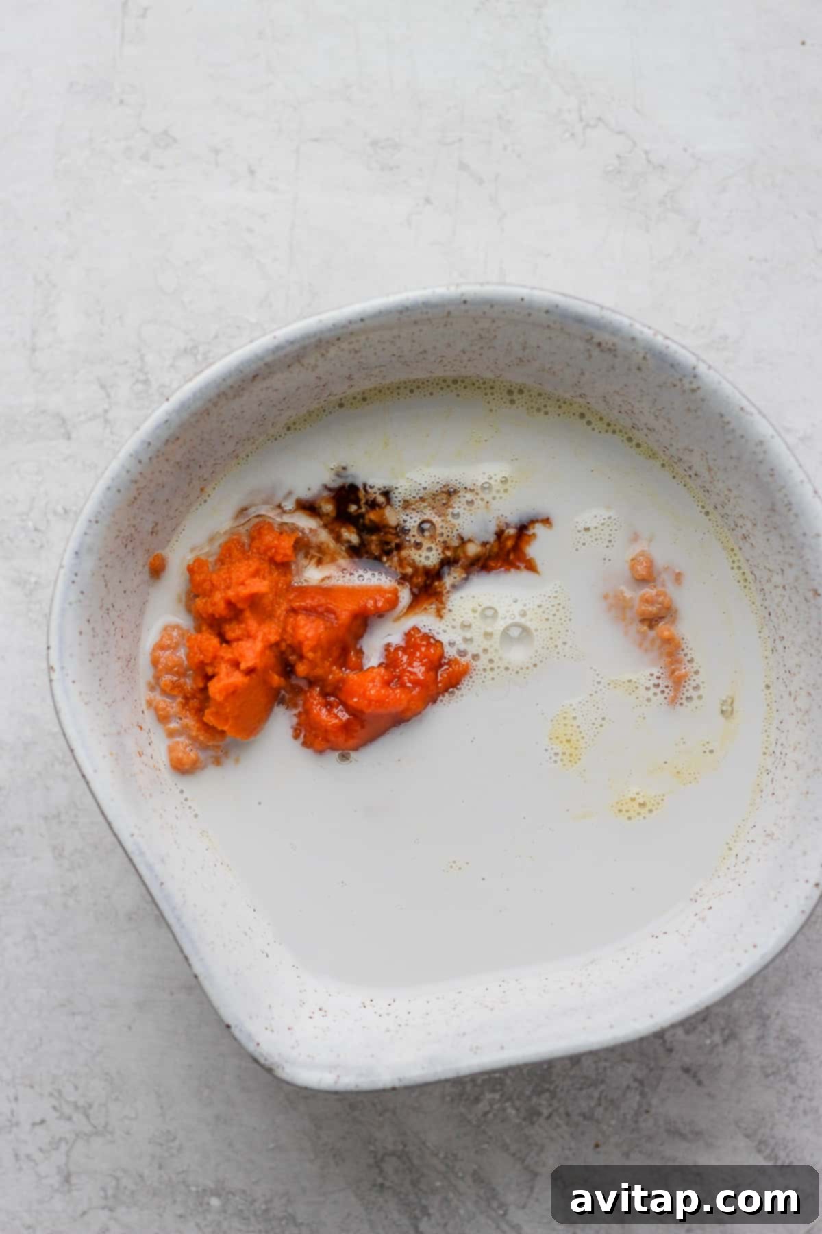 Wet Ingredients for Pumpkin Pancakes: Pumpkin Puree, Milk, and Eggs Various wet ingredients for pumpkin pancakes in a mixing bowl, including pumpkin puree and milk.