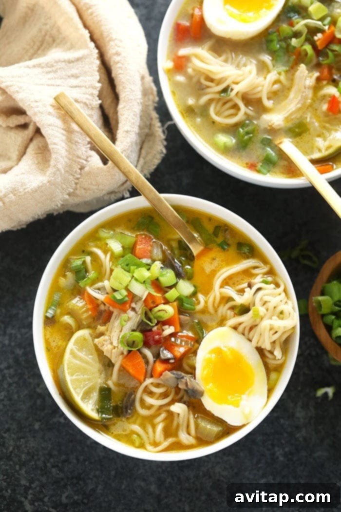 A steaming bowl of vibrant Ramen Chicken Noodle Soup, beautifully garnished with fresh green onions and a perfectly soft-boiled egg, highlighting its rich textures and inviting colors.