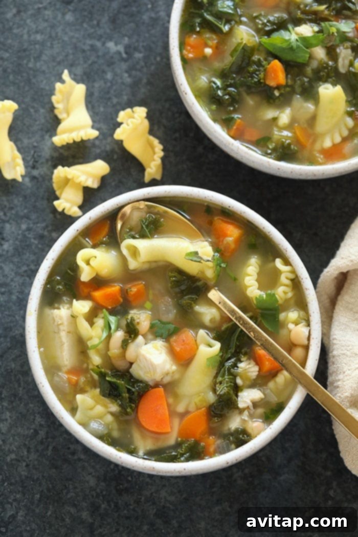 A vibrant bowl of Green Monster Spicy Chicken Noodle Soup with fresh kale and chili flakes.