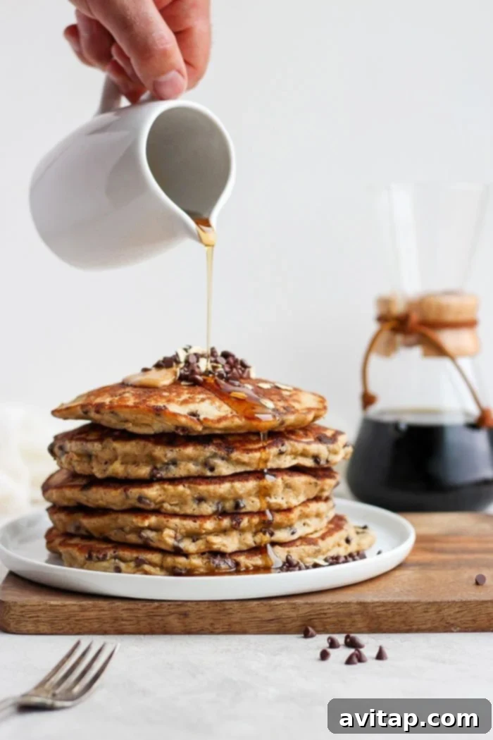 Delicious Healthy Chocolate Chip Oatmeal Pancakes Stack of healthy chocolate chip oatmeal pancakes with maple syrup, fresh berries, and a dusting of powdered sugar