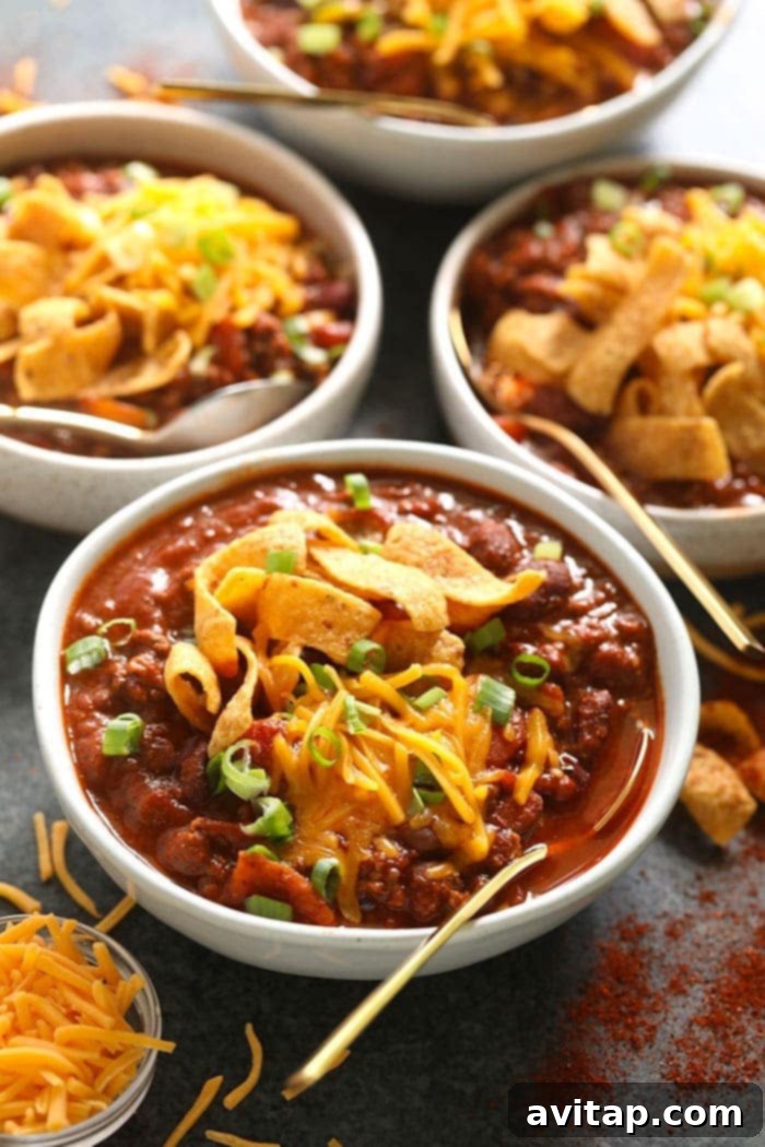 Four bowls of steaming beef chili, generously topped with crispy Fritos.