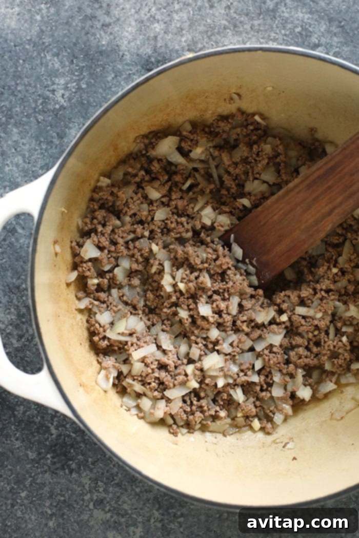 Sizzling ground beef and onions browning in a large stockpot.