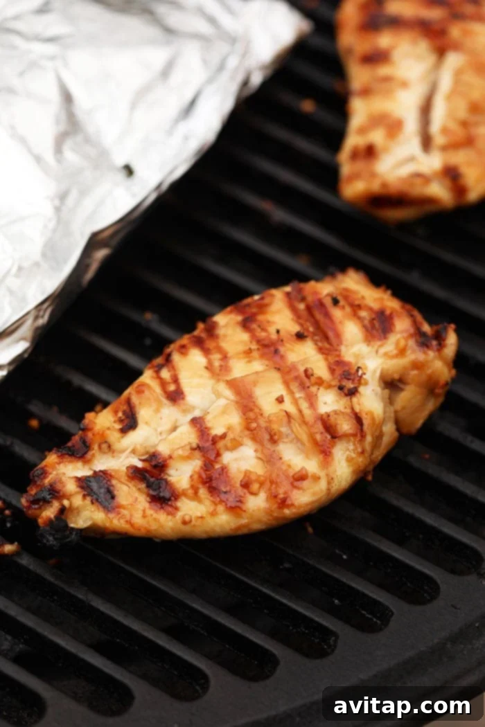 Grilled chicken breast cooking on a BBQ grill with visible grill marks.