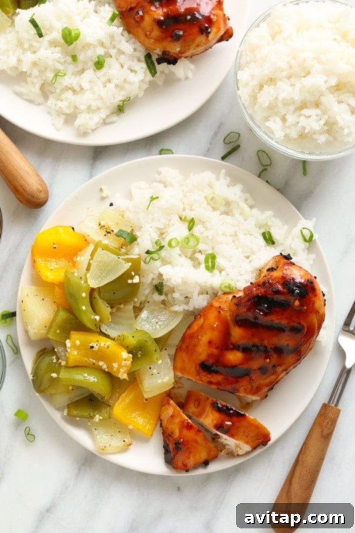 Grilled chicken breast on a plate with rice and green beans, topped with teriyaki sauce.
