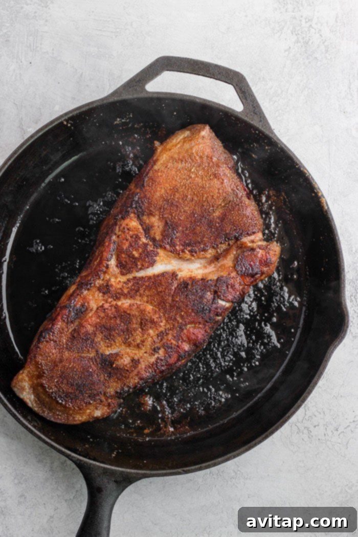 Dry rubbed pork in a cast iron skillet, ready to cook