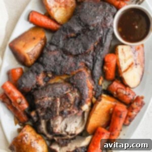 Pork roast with vegetables on a platter, coated in gravy.