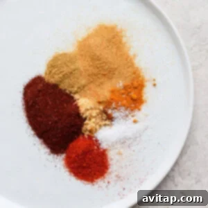 A vibrant selection of Moroccan spices, including cumin, turmeric, and ginger, arranged on a plate.