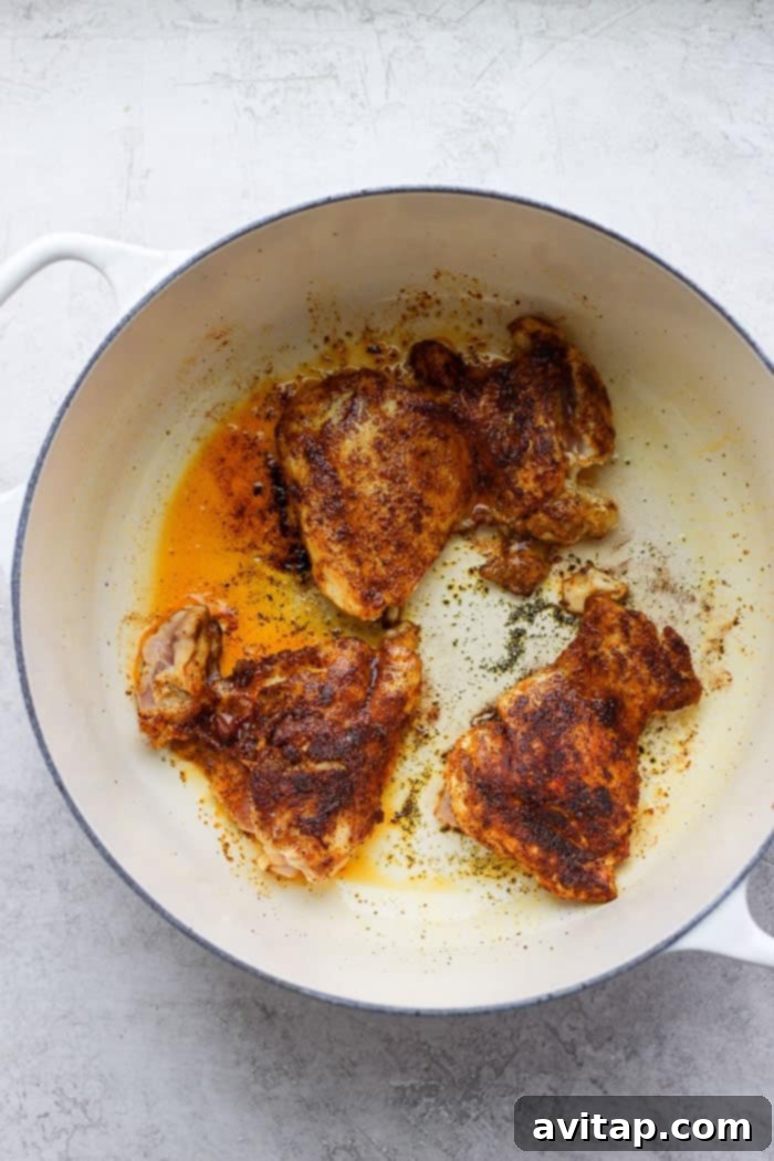 Close-up shot of chicken thighs beautifully searing in a hot Dutch oven, developing a rich golden-brown crust.