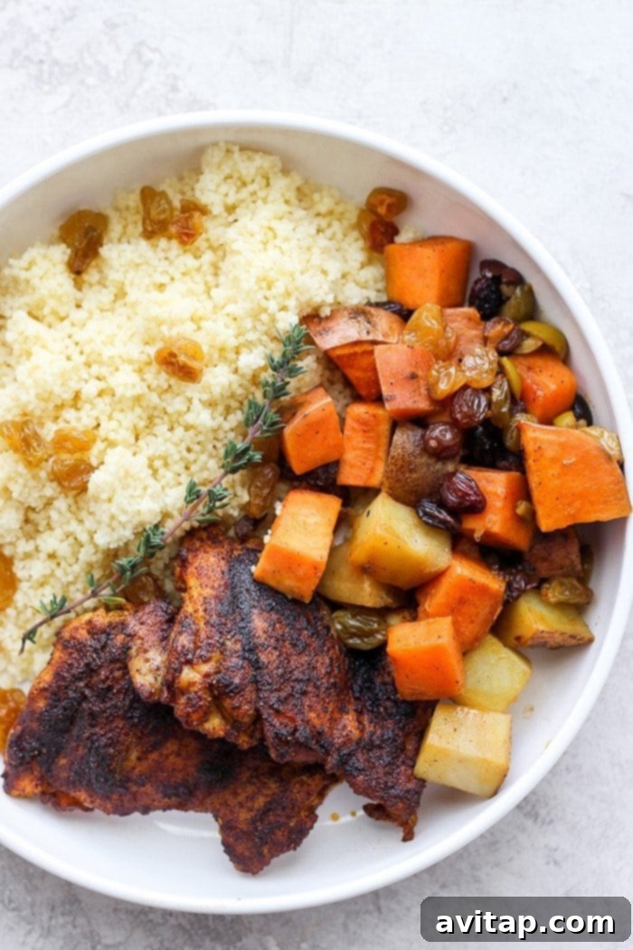 A beautifully plated serving of Moroccan chicken with tender chicken, vegetables, and couscous, garnished with fresh herbs.