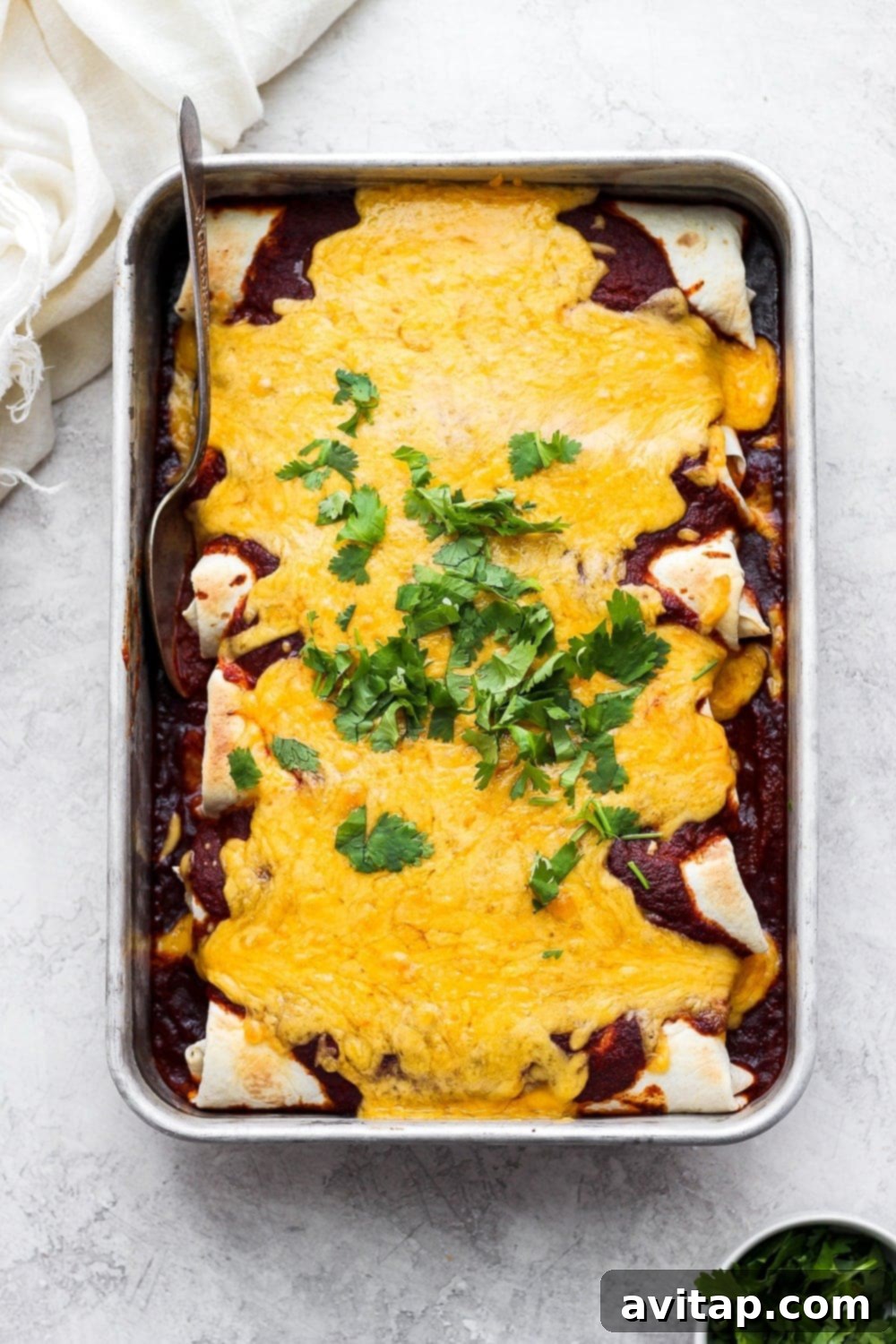 A golden pan of cheesy rotisserie chicken enchiladas, fresh from the oven, with melted cheese bubbling on top.