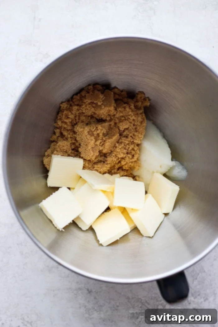 An overhead shot showcasing an organized array of fresh ingredients, including various flours, spices, butter, coconut oil, brown sugar, eggs, and molasses, prepared for baking gingersnap cookies.
