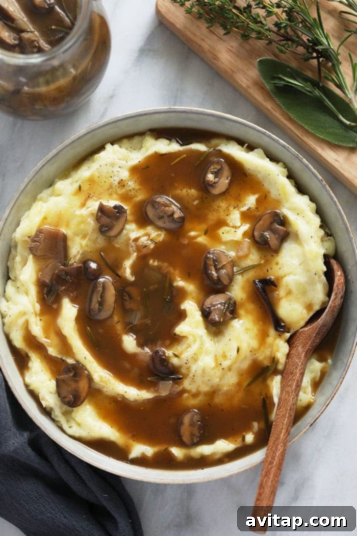 Vegetarian Mushroom Gravy generously poured over creamy mashed potatoes in a rustic bowl, garnished with fresh herbs.