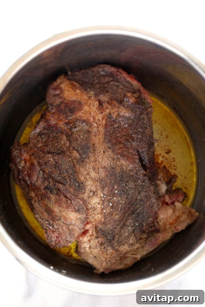 Seared chuck roast inside the Instant Pot before pressure cooking.