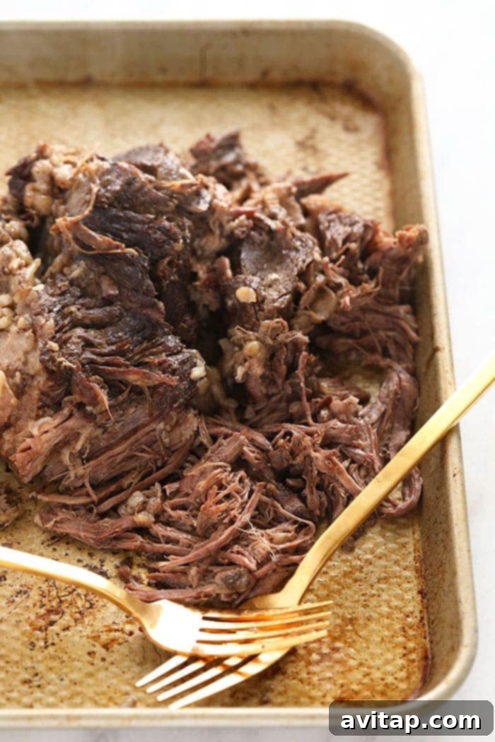 Shredded beef chuck roast on a baking sheet.