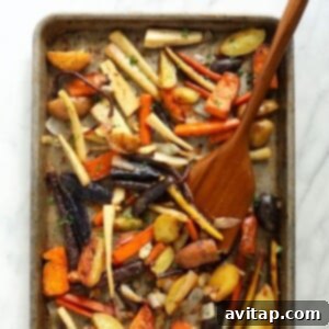 Close-up of roasted root vegetables, including carrots, potatoes, and parsnips, with a golden-brown finish.