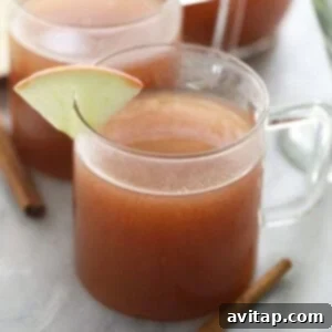 Two mugs of Spiked Apple Cider, garnished with cinnamon sticks, evoke warmth and festivity.