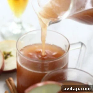 Warm spiked apple cider is poured into a cozy mug, ready for a garnish and enjoyment.