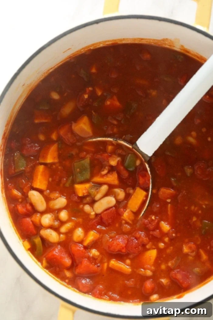 A large pot of simmering vegetarian chili, rich in color and texture, with steam gently rising, promising warmth and comfort.