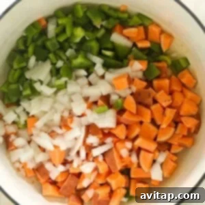 A vegetarian chili with onions and peppers in a white bowl.