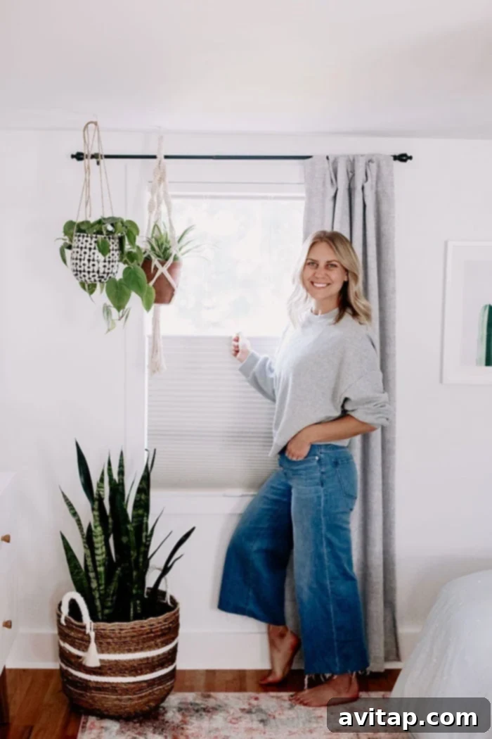 Woman pulling down a sleek, modern window shade, showcasing the new custom window treatments in her home.