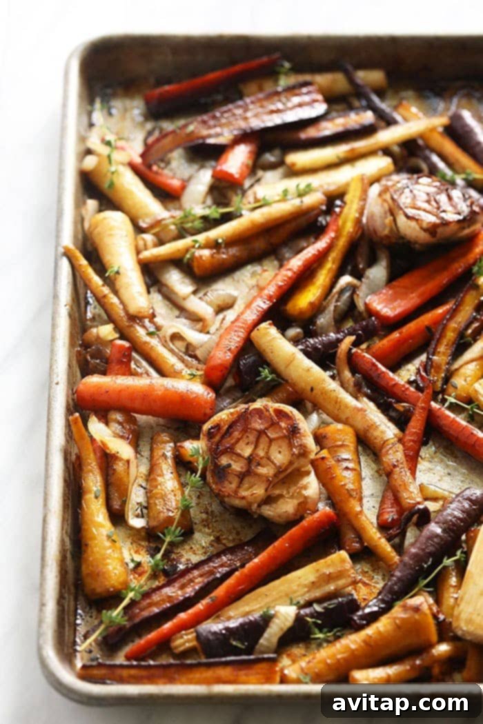 These Honey Balsamic Roasted Carrots are the ultimate holiday side dish! The combination of sweet and savory from the honey balsamic + perfectly roasted carrots, onions and garlic make this side a perfect addition to any holiday table. Beautifully caramelized honey balsamic roasted carrots on a baking pan, ready to serve.
