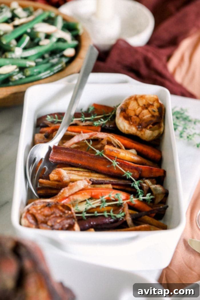 These Honey Balsamic Roasted Carrots are the ultimate holiday side dish! The combination of sweet and savory from the honey balsamic + perfectly roasted carrots, onions and garlic make this side a perfect addition to any holiday table. A close-up of honey balsamic roasted carrots and tender garlic cloves elegantly plated at a holiday table setting.