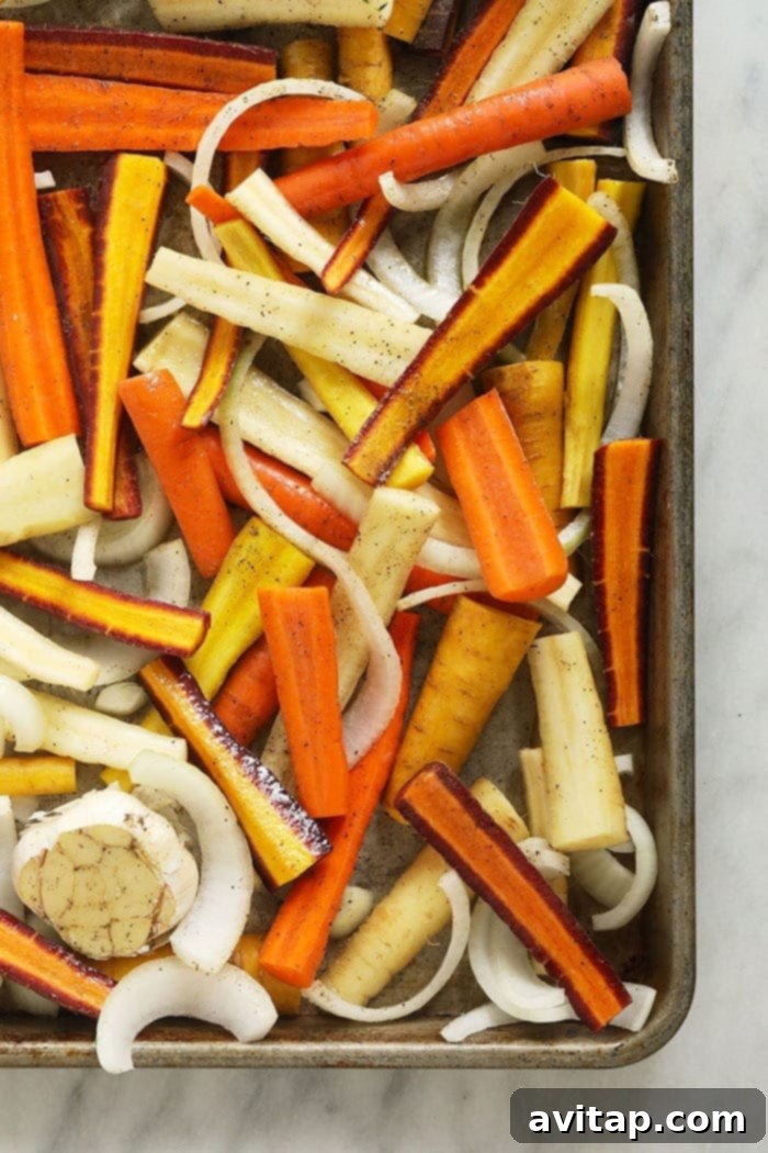 These Honey Balsamic Roasted Carrots are the ultimate holiday side dish! The combination of sweet and savory from the honey balsamic + perfectly roasted carrots, onions and garlic make this side a perfect addition to any holiday table. Freshly cut carrots and onions arranged neatly on a baking tray, ready for roasting.