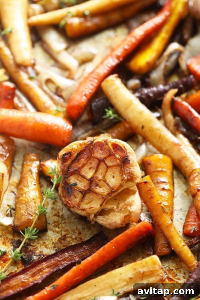 These Honey Balsamic Roasted Carrots are the ultimate holiday side dish! The combination of sweet and savory from the honey balsamic + perfectly roasted carrots, onions and garlic make this side a perfect addition to any holiday table. Close-up of perfectly roasted carrots and garlic, glistening with honey balsamic glaze, looking incredibly appetizing.