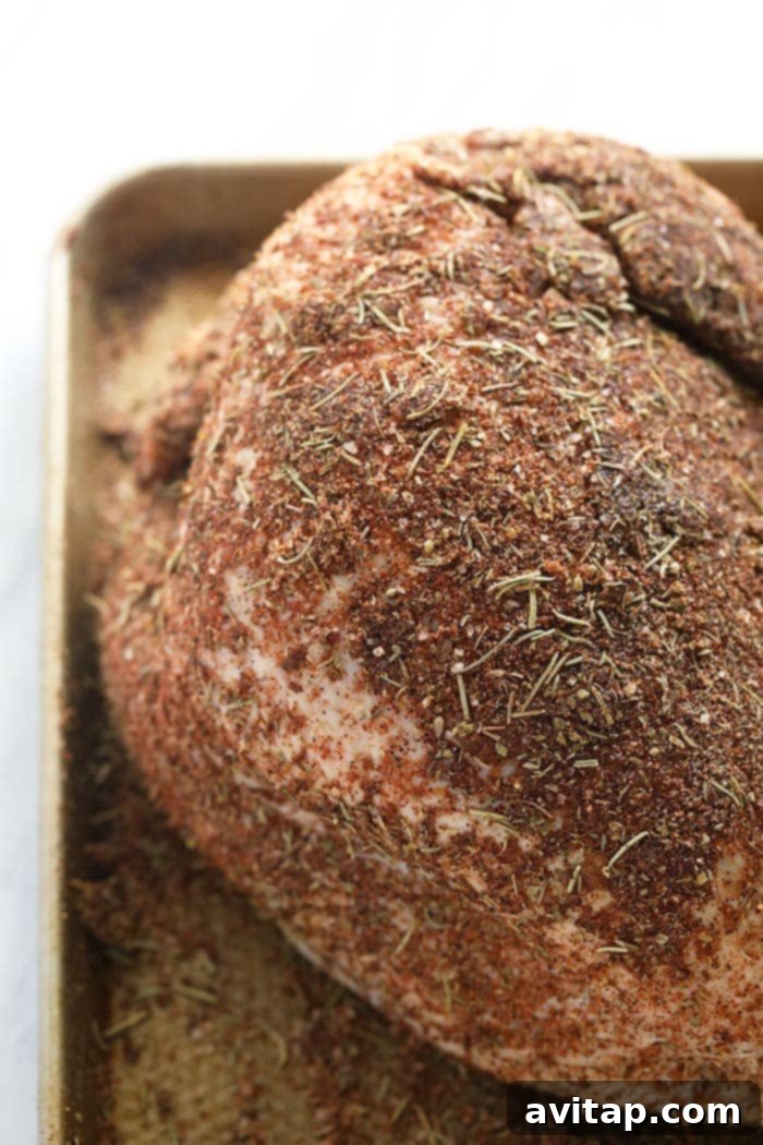 Raw turkey breast generously patted with a flavorful, aromatic dry seasoning blend.