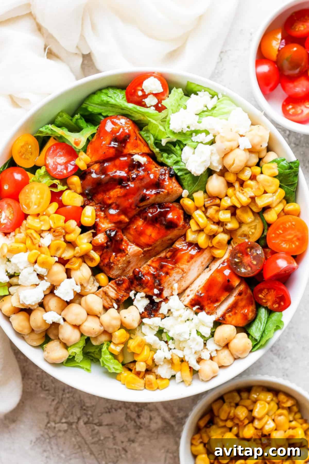 A vibrant BBQ chicken salad featuring grilled chicken, corn, cherry tomatoes, and garbanzo beans in a large bowl, ready to be served.