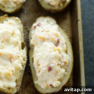 Double-Baked Potato Perfection 4 Four generously filled twice baked potatoes, arranged on a baking sheet, showcasing their bountiful and cheesy topping before the final bake.