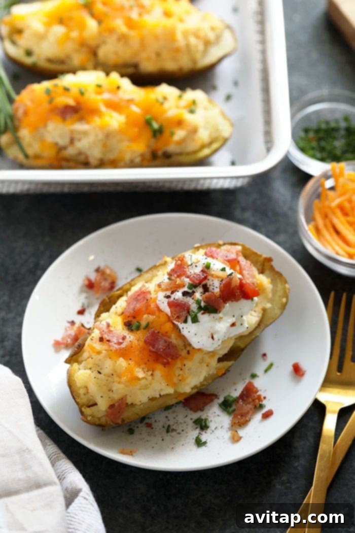 Gourmet Twice Baked Potato with Toppings A finished twice baked potato adorned with crispy bacon bits, fresh chives, and a dollop of Greek yogurt, served on a white plate.