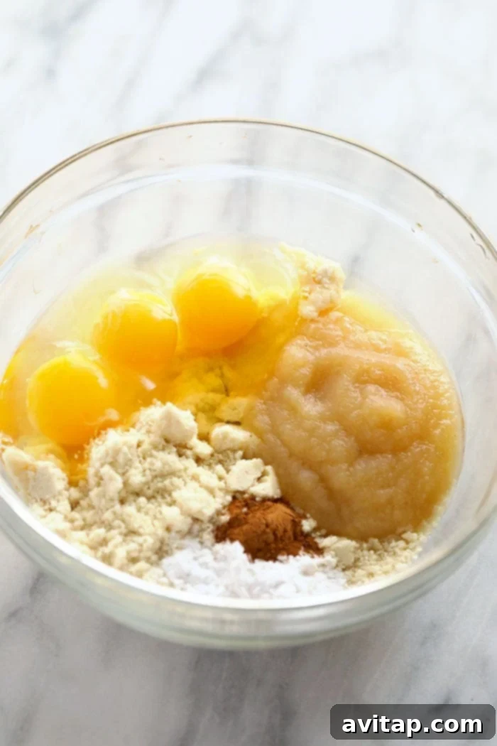 A bowl filled with natural ingredients for applesauce pancakes, highlighting the wholesome components like applesauce, eggs, and almond flour.