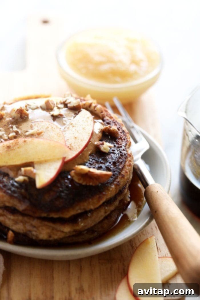 Grain-free applesauce pancakes topped with fresh apple slices and a hint of cinnamon, presented as a delectable and healthy meal.