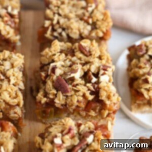 Apple crisp bars with granola and pecans, resembling apple pie bars, displayed on a cutting board.