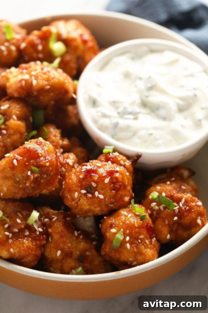 A vibrant bowl of crispy sweet chili cauliflower wings, garnished with fresh herbs and ready to be enjoyed.