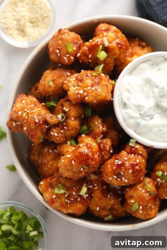 A bowl of finished sweet chili cauliflower wings with a side of creamy dipping sauce, ready to be served.